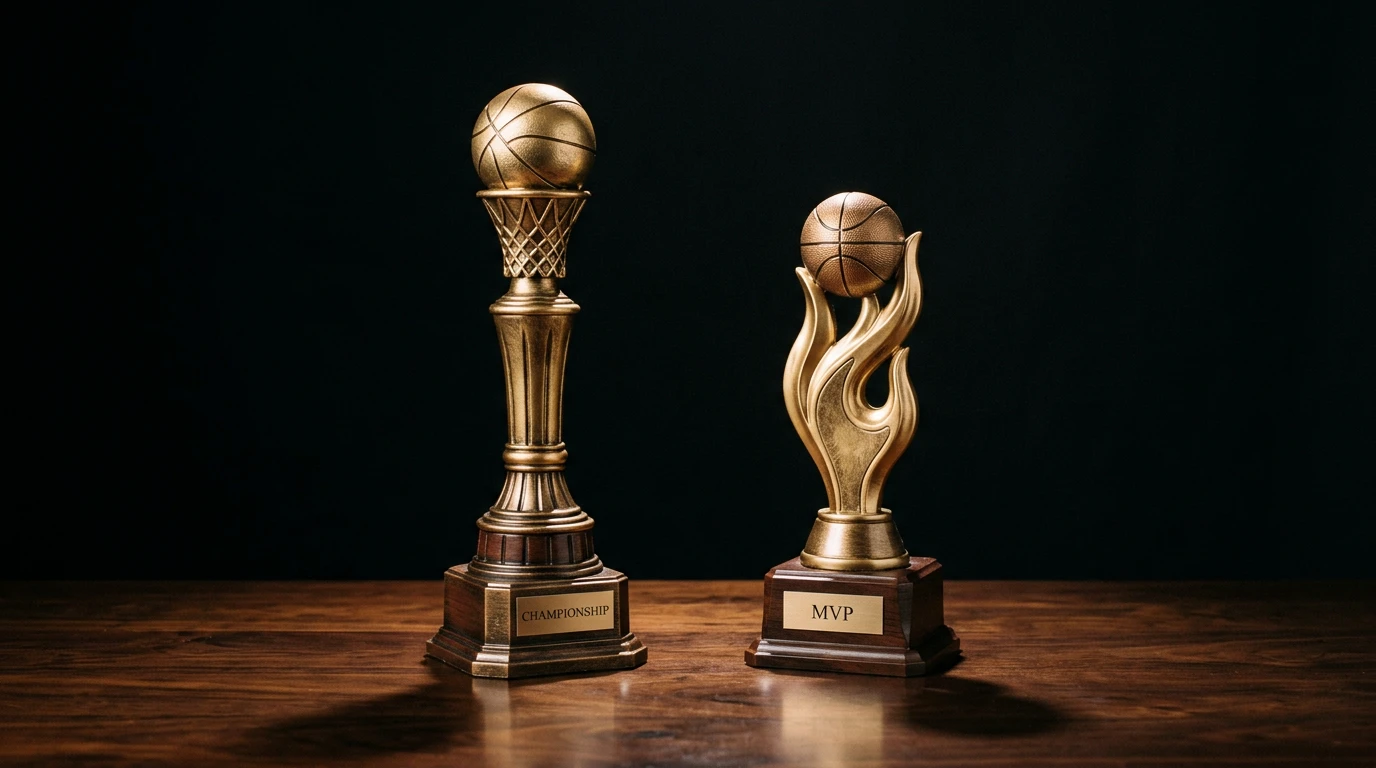 Studio still life of a generic basketball championship trophy alongside an MVP-style trophy on a dark wooden surface